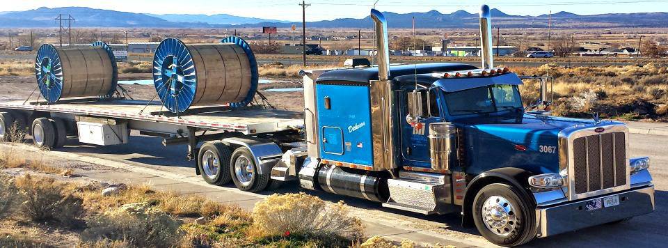 Photo of a BTI Tractor hauling large spools on the road.