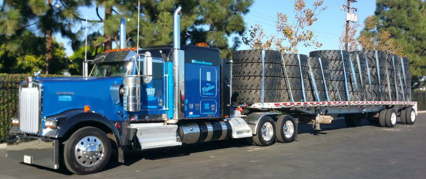 Photo of a BTI Tractor on the side of a ride with tractor tires on the flatbed.