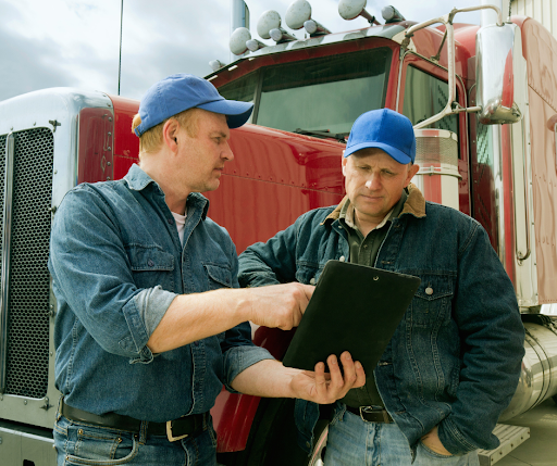 Two truckers in blue hats discuss an Independent trucking job.